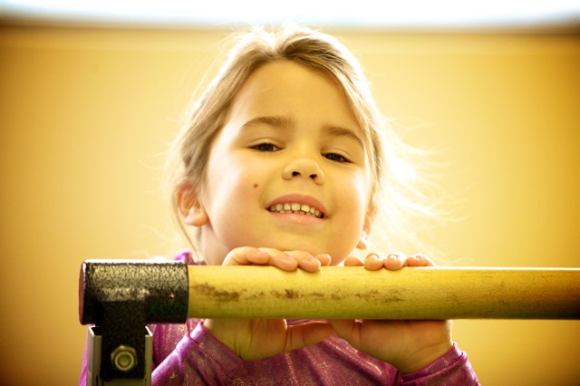 Young girl resting her chin on a gymnastics bar